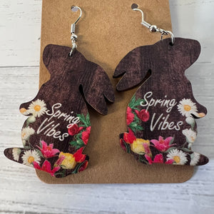 Wooden bunny-shaped earrings with floral designs and 'Spring Vibes' text on a brown card.