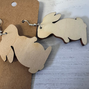 Wooden rabbit-shaped earrings on a gray surface with a brown card.