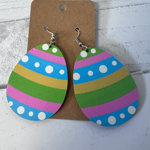 Colorful striped earrings with polka dots on a brown card against a white background