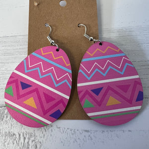 Pink geometric patterned earrings on a cardboard backing with a white background