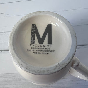 Mug with 'Magenta Exclusive' text on a white wooden surface