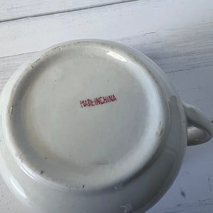 White ceramic dish with 'MADE IN CHINA' text on a light wooden surface