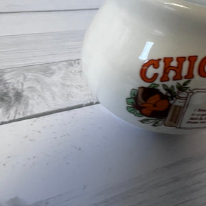 White ceramic bowl with 'Chicken soup' branding on a wooden surface