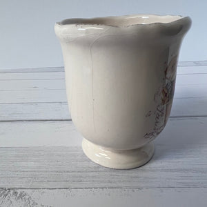 White ceramic vase with text on a light wooden surface