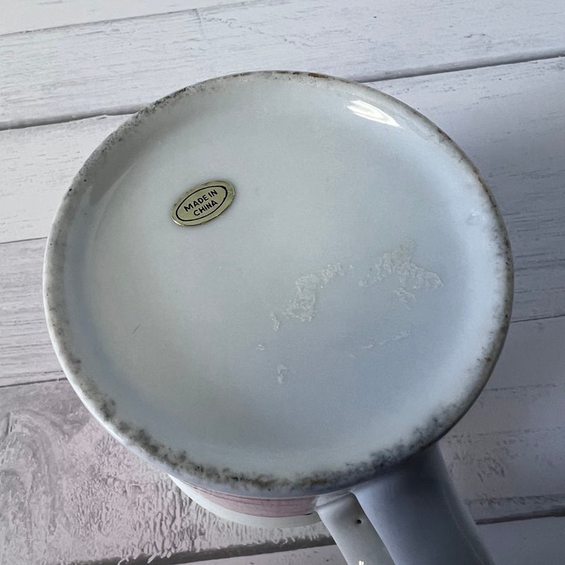White ceramic mug with speckled design on a light wooden surface