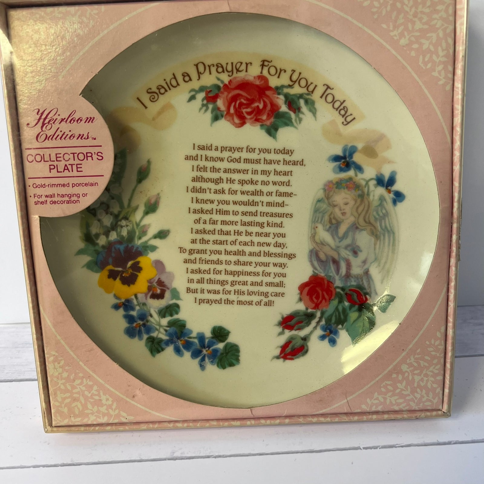 A round ceramic collector's plate with floral illustrations and a printed prayer, presented inside its original pink and gold Miriambox packaging.