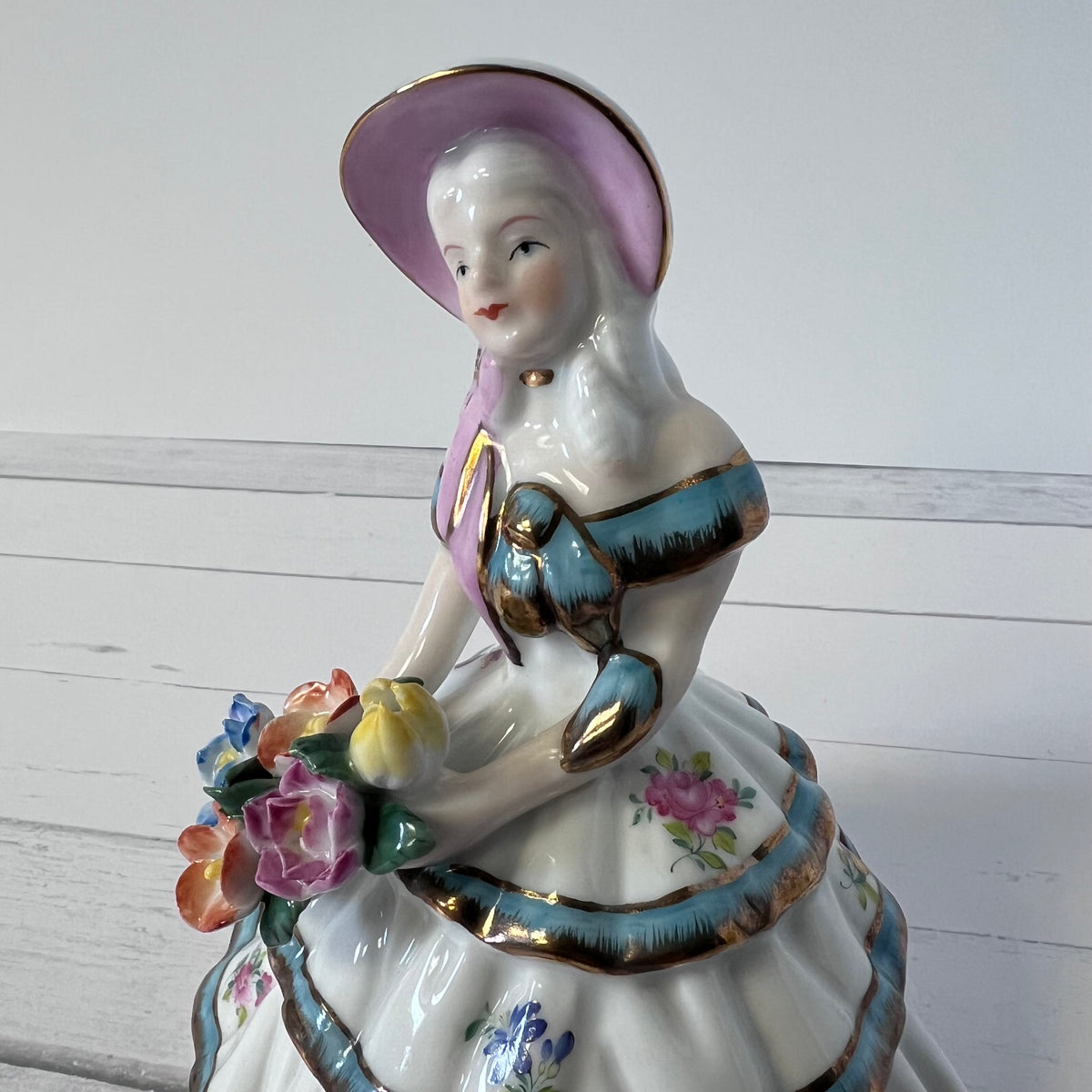 Porcelain Girl Figurine with Blue & Gold Accents – Holding Flowers