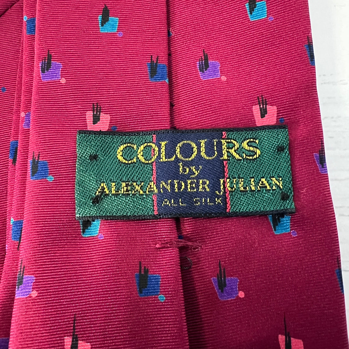 Close-up of a red tie with a 'Colours by Alexander Julian' label.