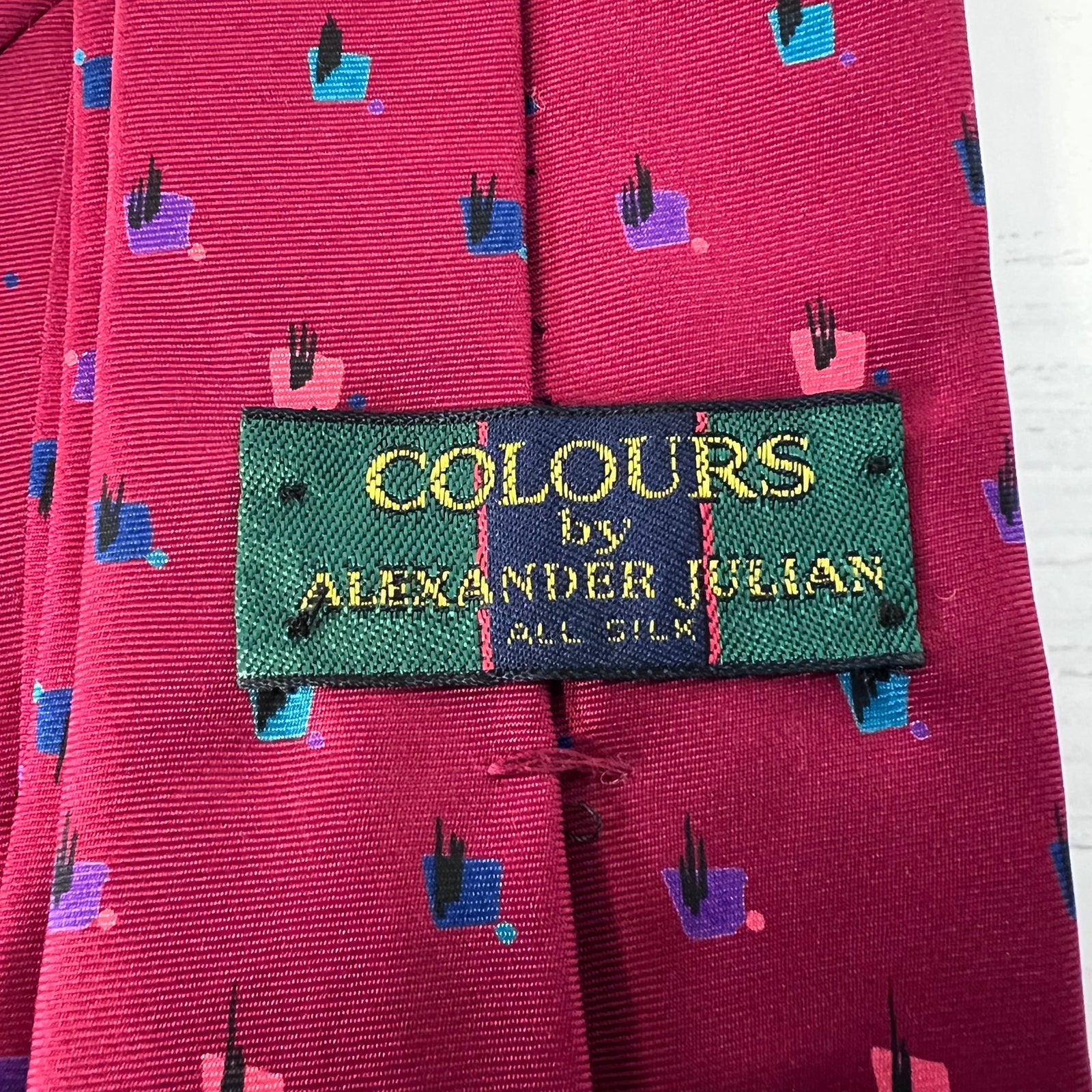 Close-up of a red tie with a 'Colours by Alexander Julian' label.