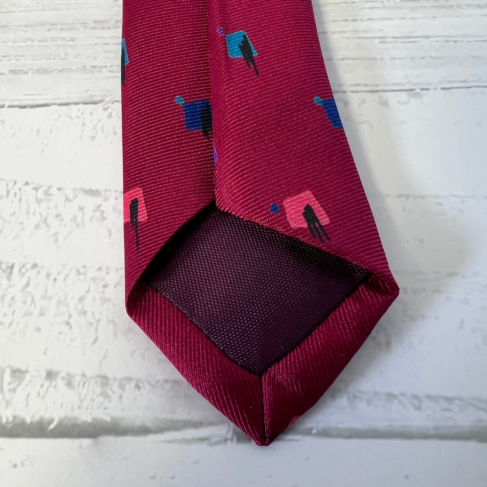 Maroon tie with geometric pattern on a textured white surface
