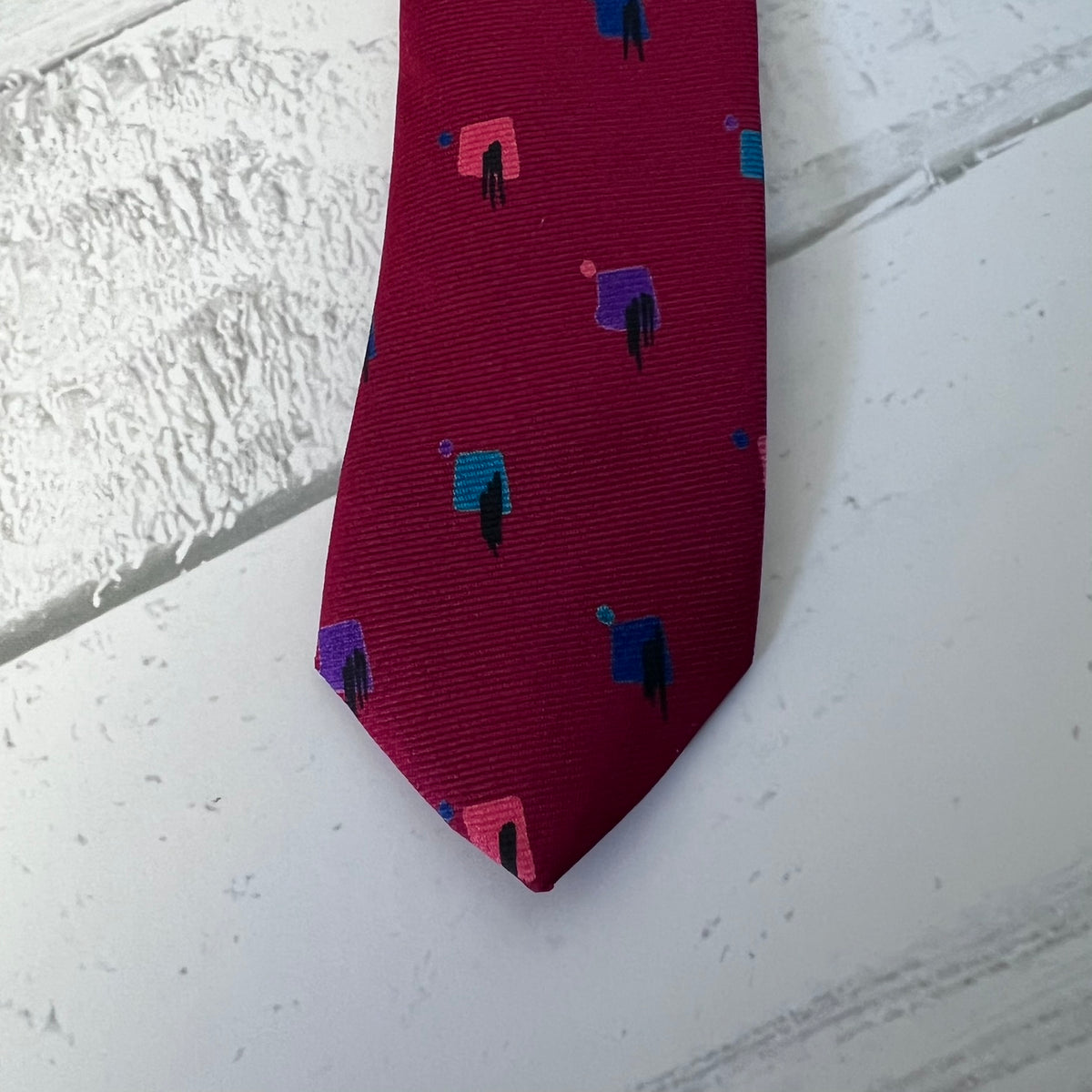 Red tie with geometric pattern on a textured white surface