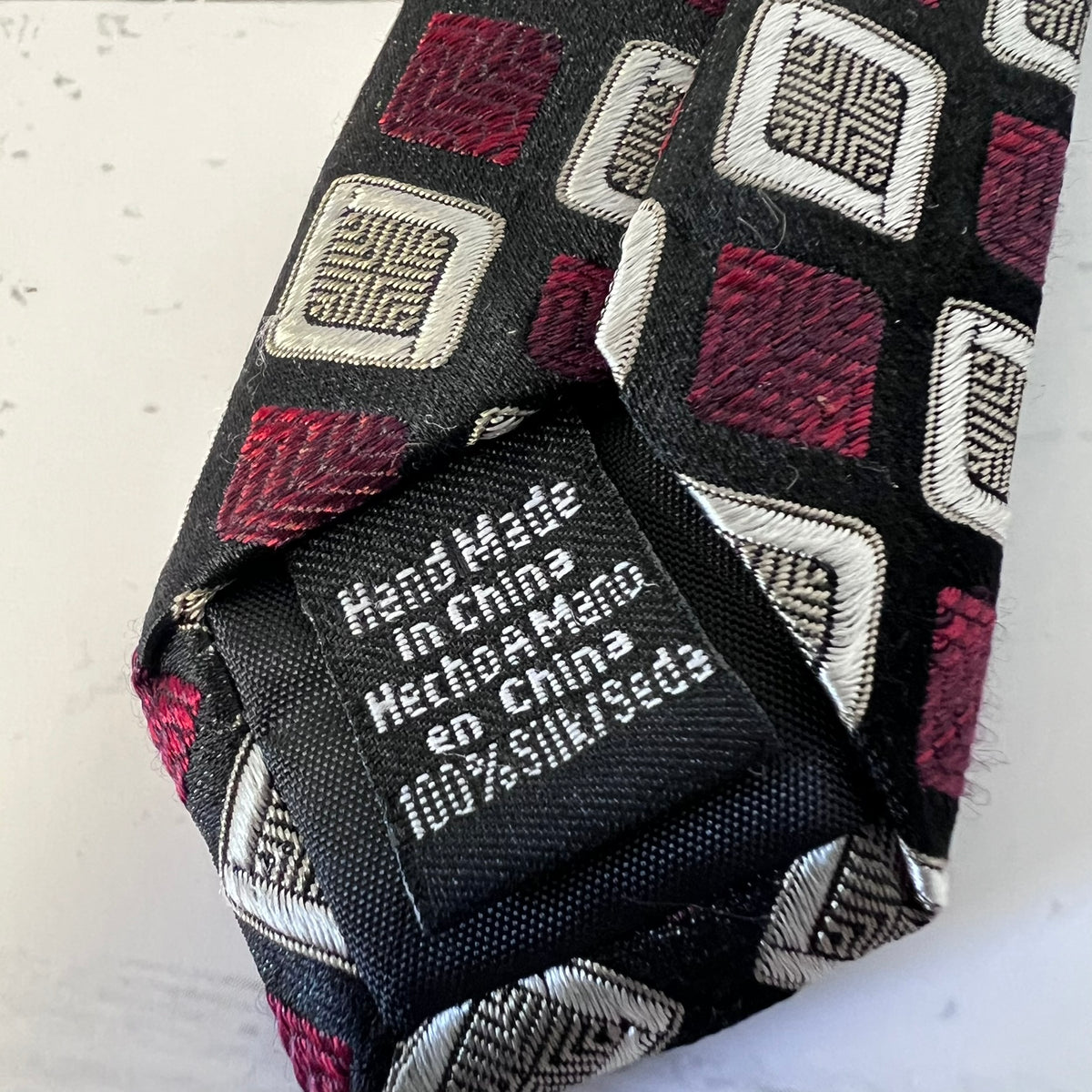 Patterned tie with a label indicating 'Hand Made in China' on a light background