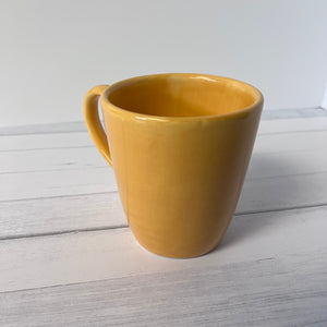 Yellow mug on a light wooden surface