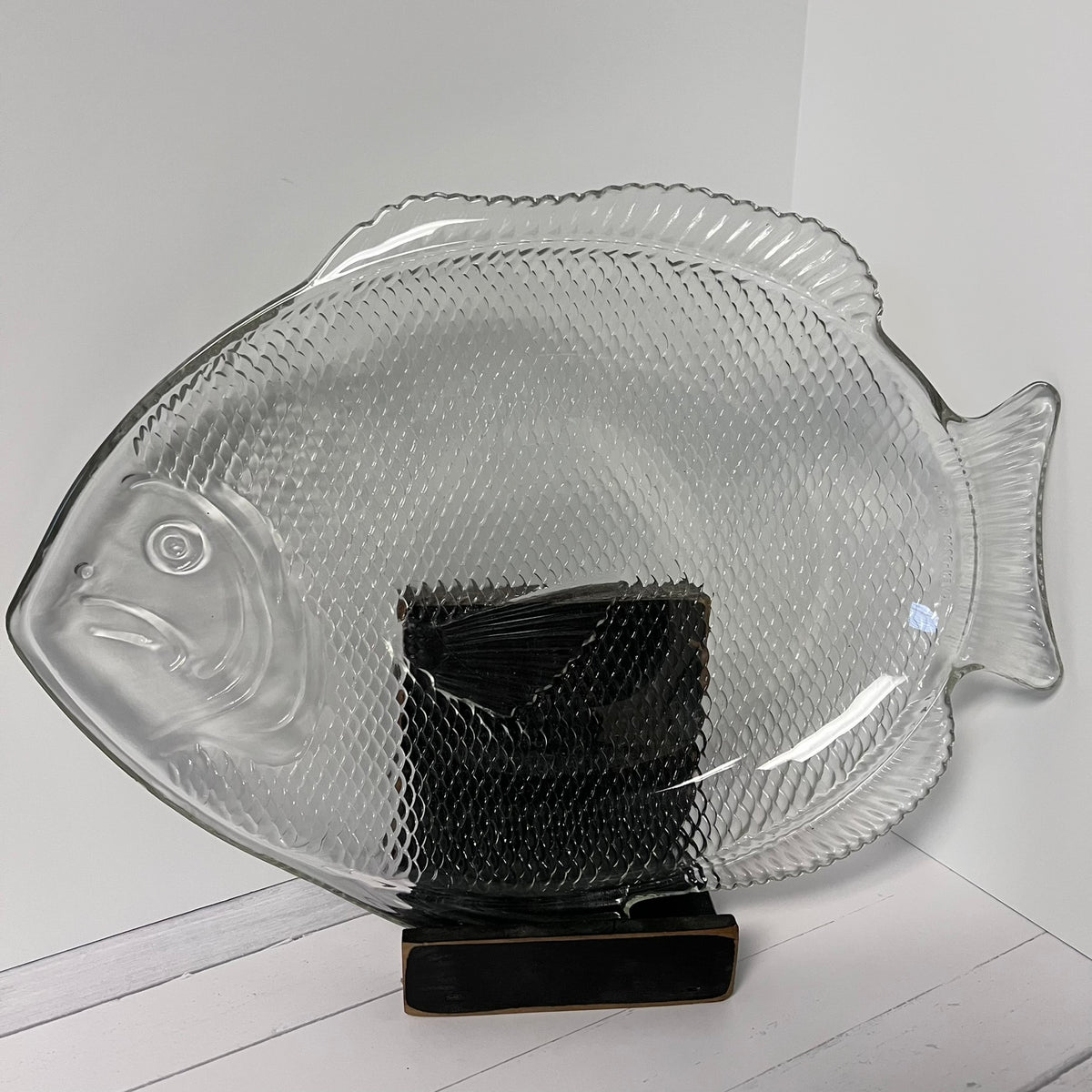 Clear glass fish-shaped platter on a white surface