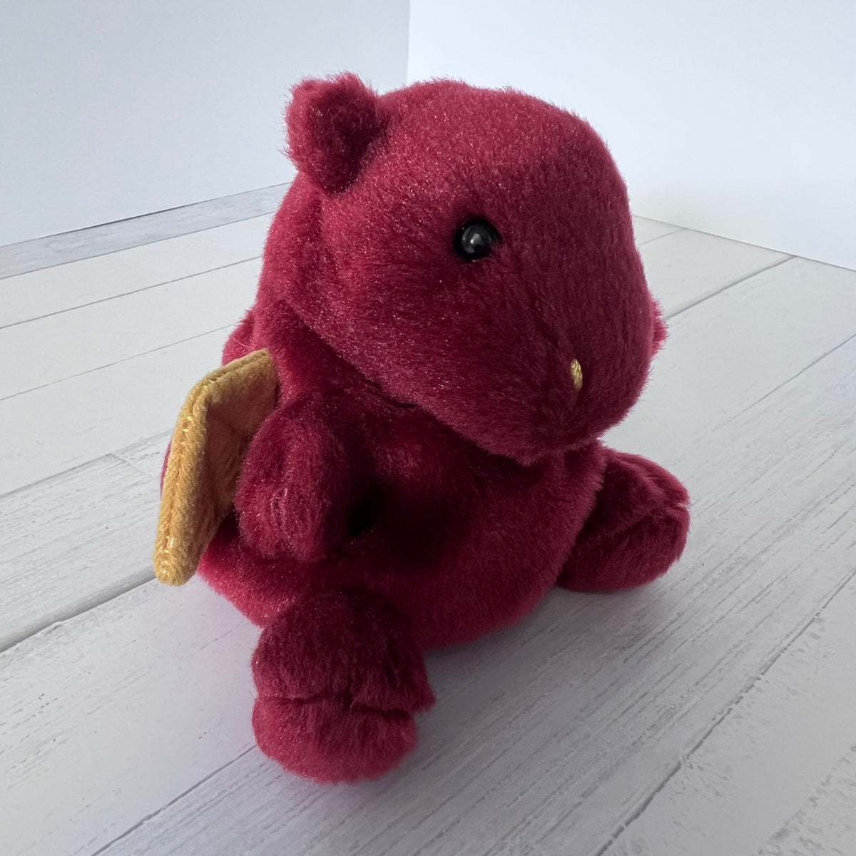Plush dragon toy on a white wooden floor