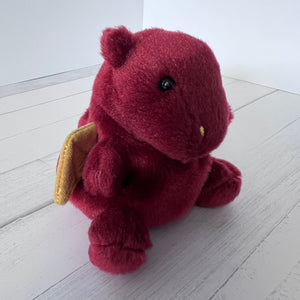 Plush dragon toy on a white wooden floor