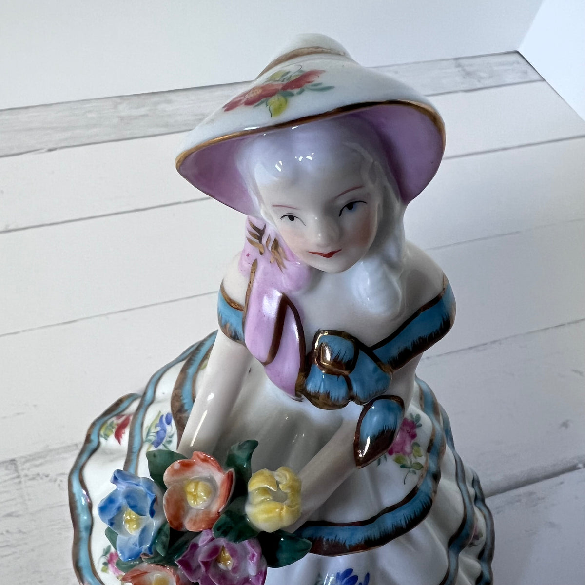 Porcelain Girl Figurine with Blue & Gold Accents – Holding Flowers