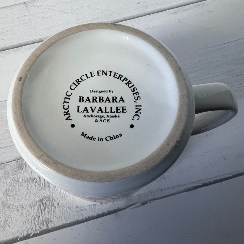 Ceramic mug with 'Arctic Circle Enterprises, Inc.' branding on a light wooden surface