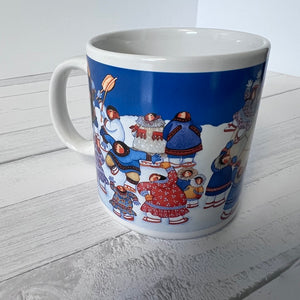 Mug with a colorful design of people in winter clothing on a white wooden surface.