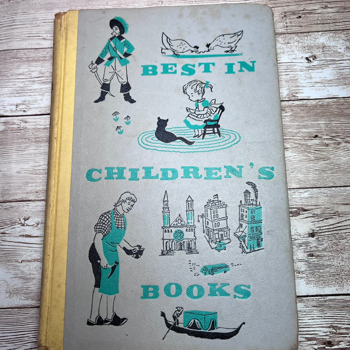 Vintage children's book with a light gray cover featuring teal and black illustrations and the title 'BEST IN CHILDREN'S BOOKS,' photographed on a rustic wood surface.
