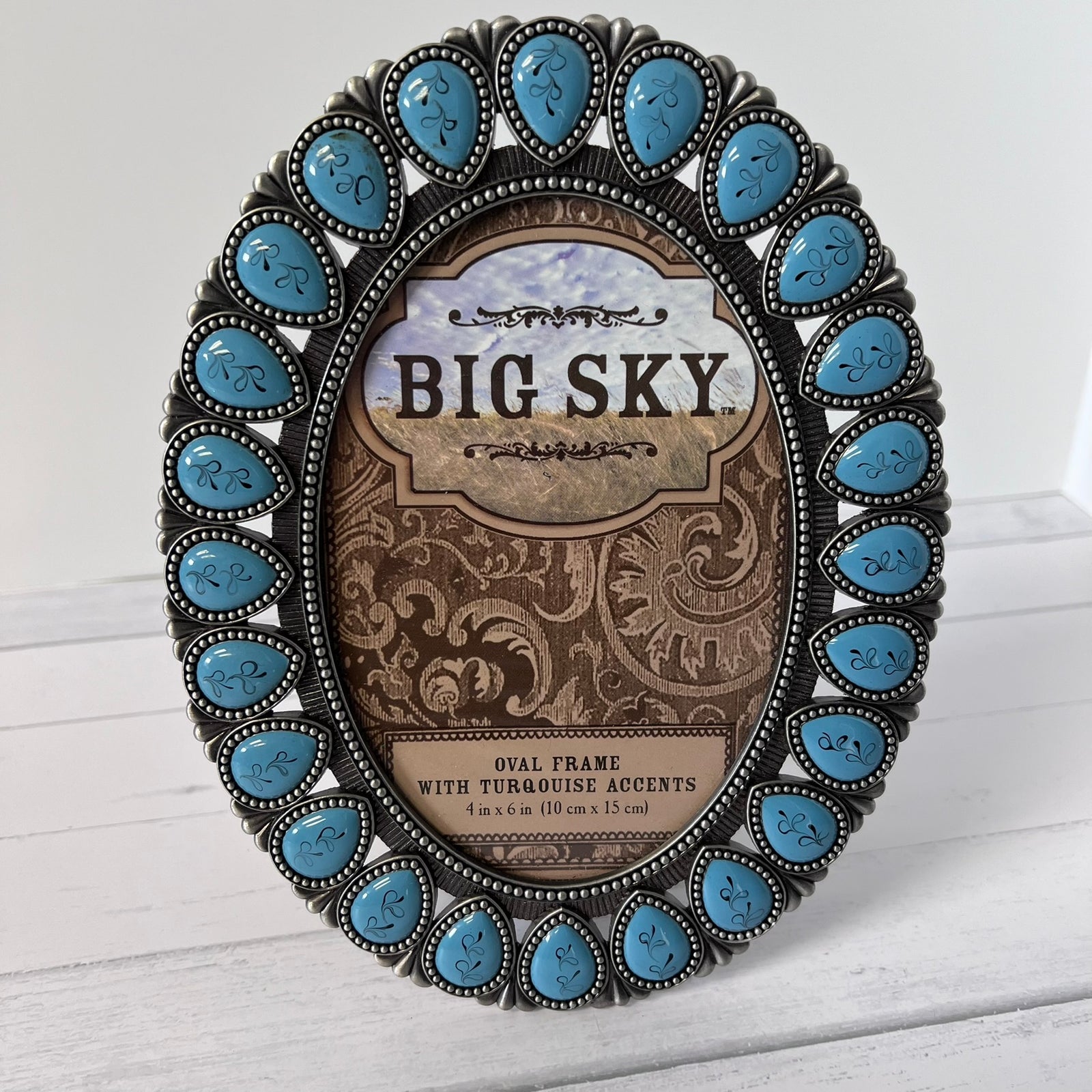 An oval picture frame with a Southwestern-style silver-toned border set with turquoise stones. The center insert reads 'BIG SKY' and indicates it is an oval frame with turquoise accents, 4 in x 6 in (10 cm x 15 cm).