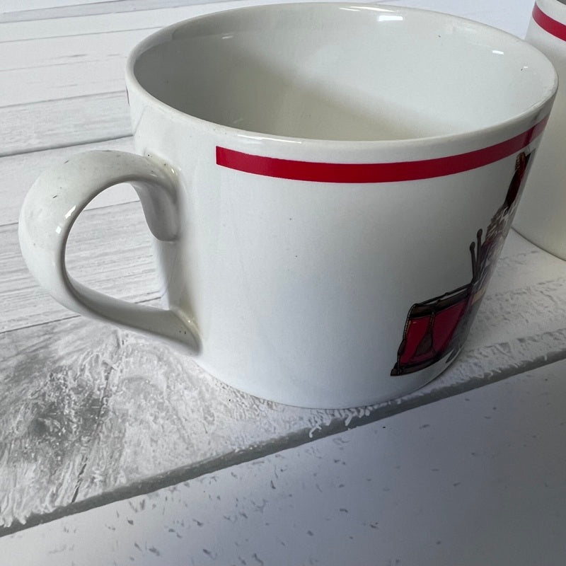 White mug with a red stripe and logo on a light wooden surface