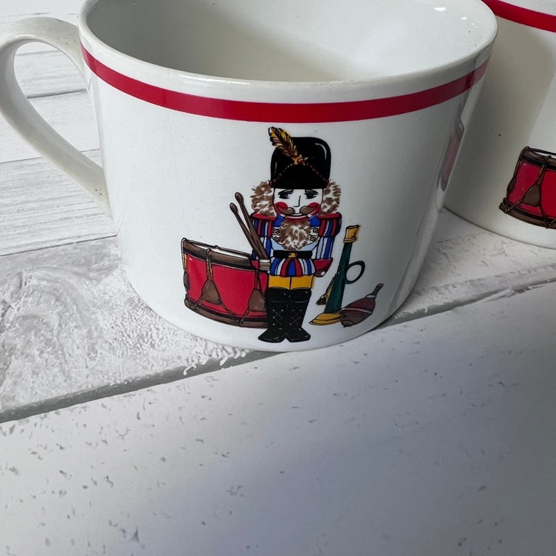 White mug with a decorative design of a drummer boy on a white surface