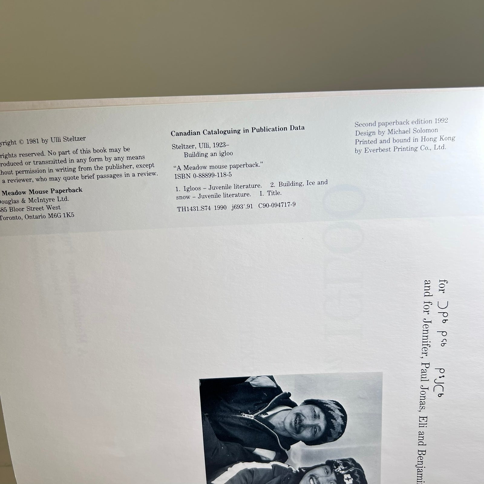 A photographed interior page from a book showing publication data, copyright text, and a black-and-white cover illustration of a person holding a rifle. The page is slightly tilted and photographed in a real environment rather than as a clean catalog shot.