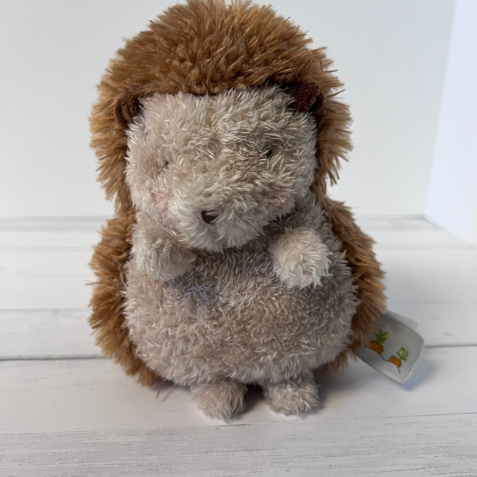 Plush hedgehog toy on a white wooden surface