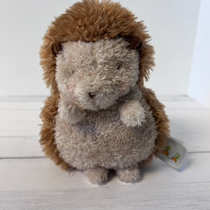 Plush hedgehog toy on a white wooden surface