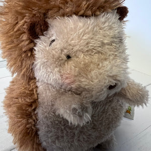 Plush toy resembling a sheep with a tag on a white floor