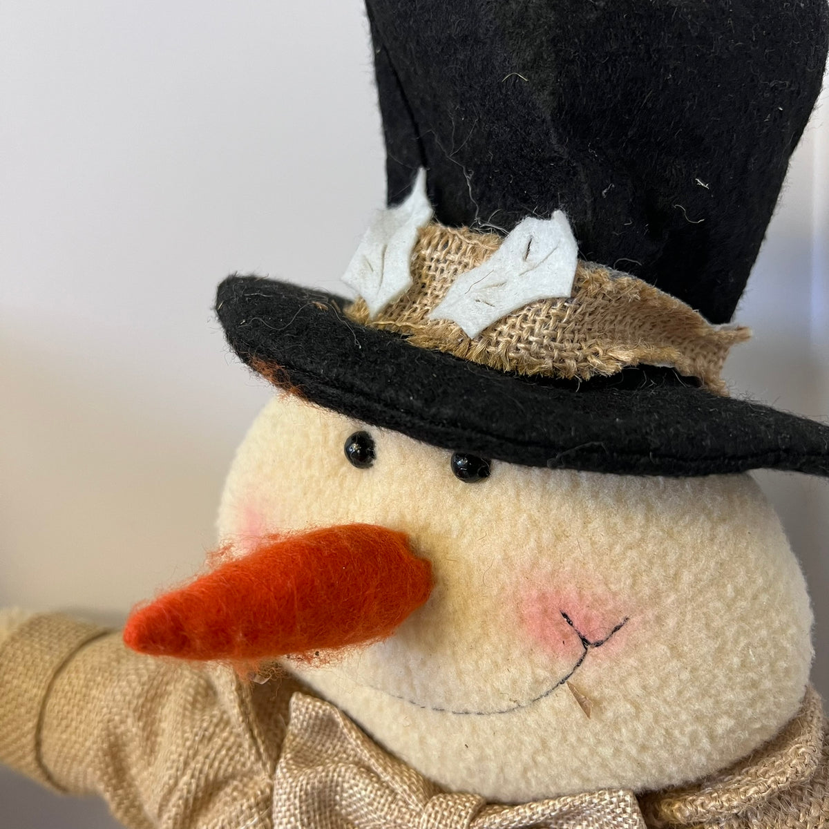 Close-up of a decorative snowman with a black top hat and orange carrot nose.