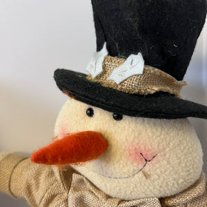 Close-up of a decorative snowman with a black top hat and orange carrot nose.