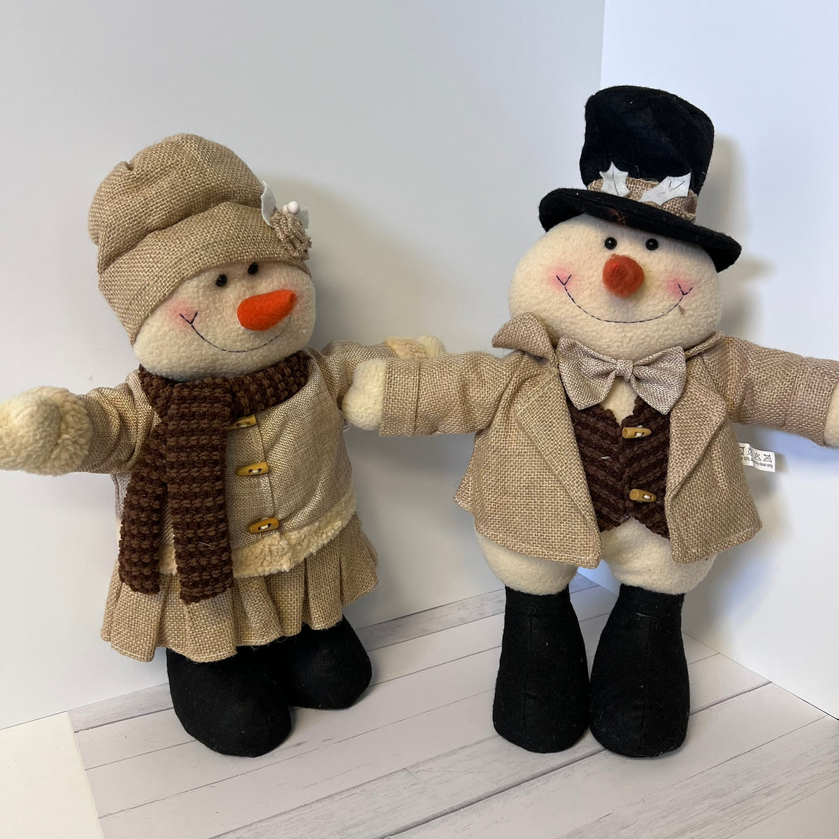 Two decorative snowmen dressed in winter clothing on a white background