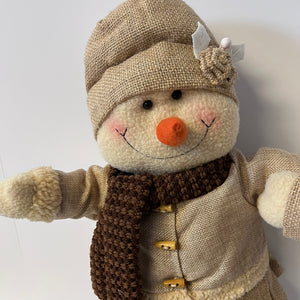 Stuffed snowman toy with a textured hat, scarf, and coat on a white background