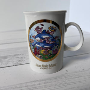 Mug with a decorative design of dolphins and fish on a white wooden surface