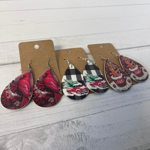 Set of Christmas-themed earrings on brown paper cards against a white wooden background