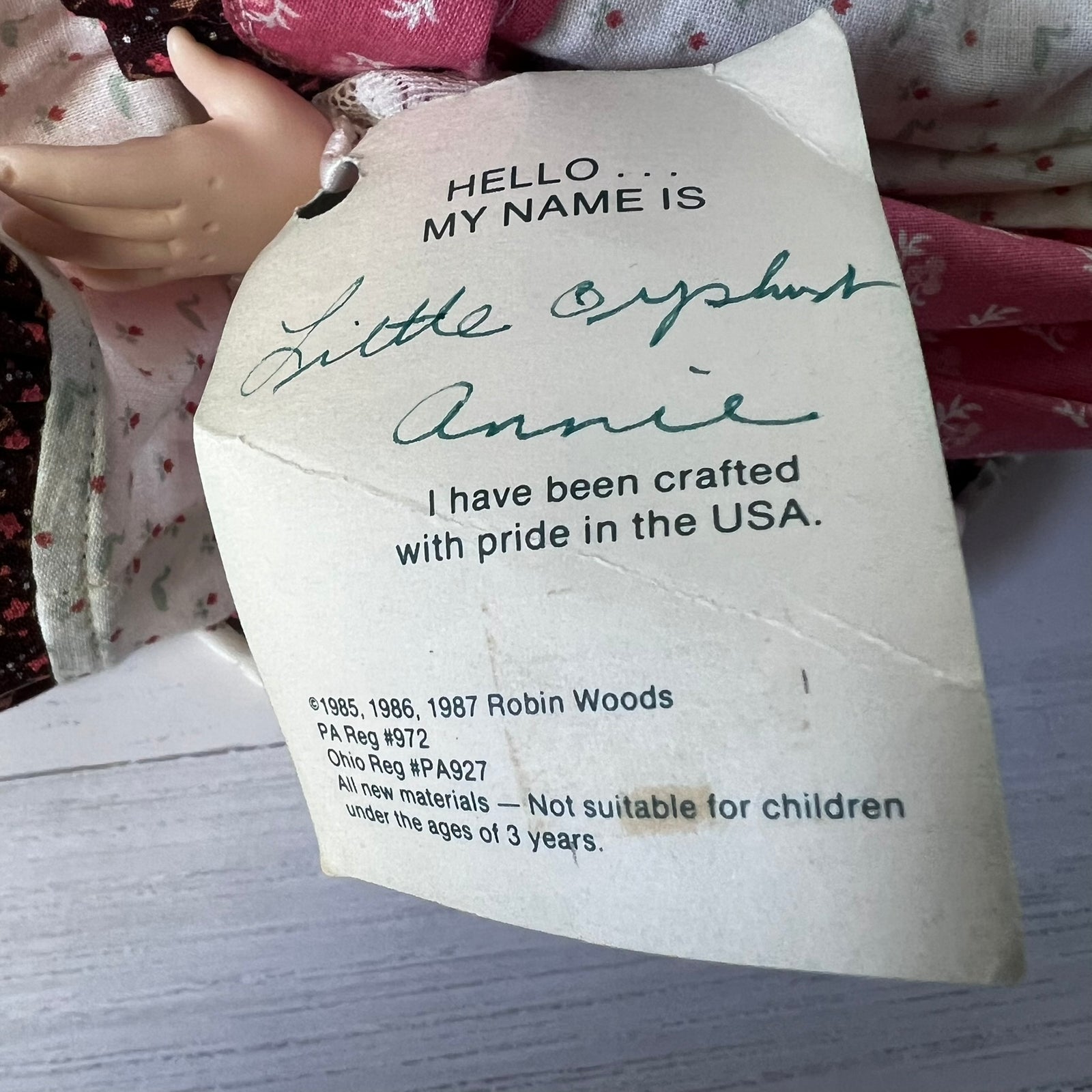 A vintage doll tag attached to a doll, reading 'HELLO.