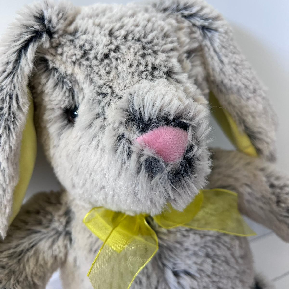 Plush bunny toy with a yellow bow on a white background