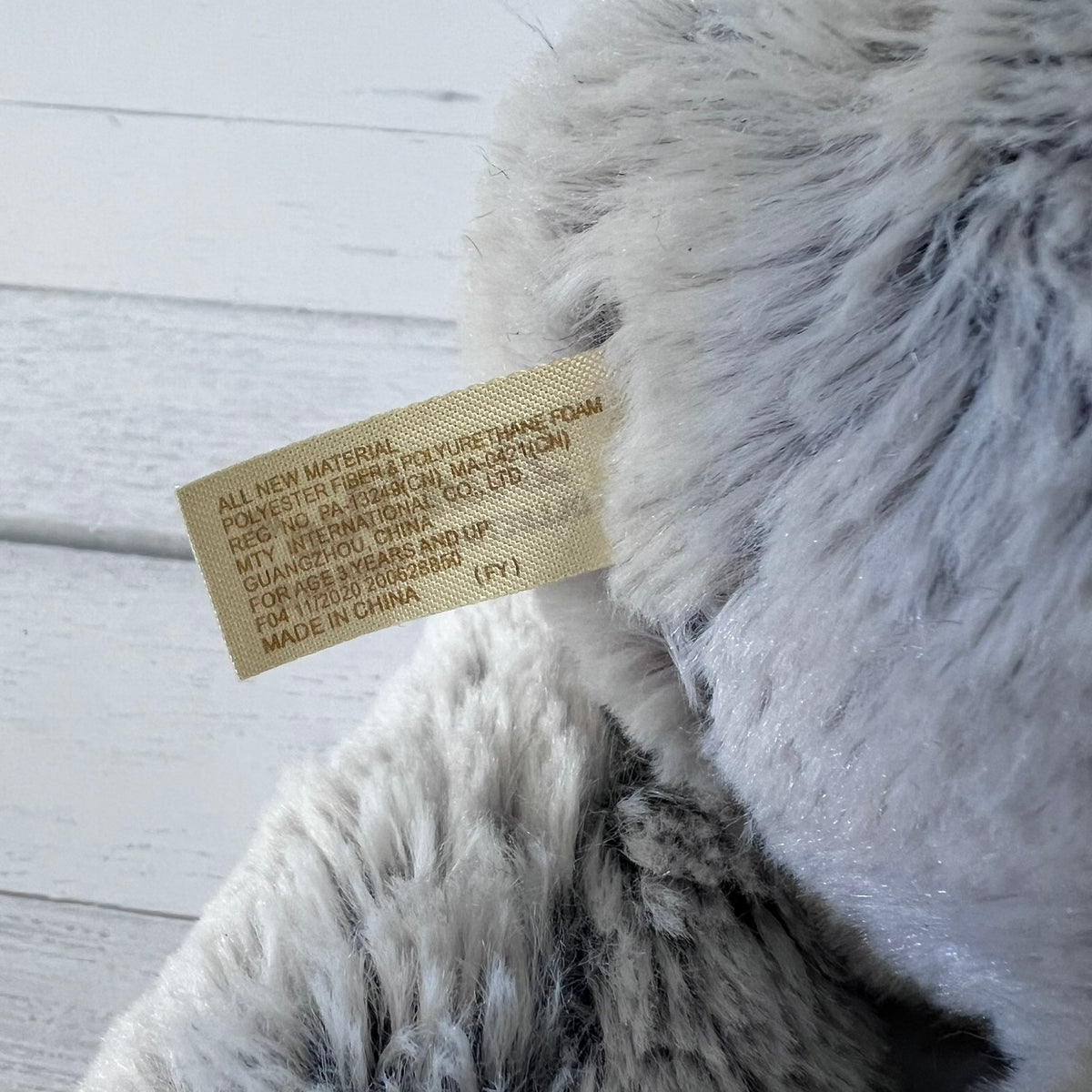 Close-up of a fluffy gray pillow with a label on a light wooden surface