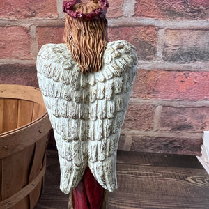 Decorative angel statue with a wooden barrel and brick wall background