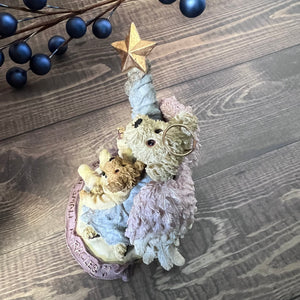 Decorative angel with teddy bears and a star on a wooden surface