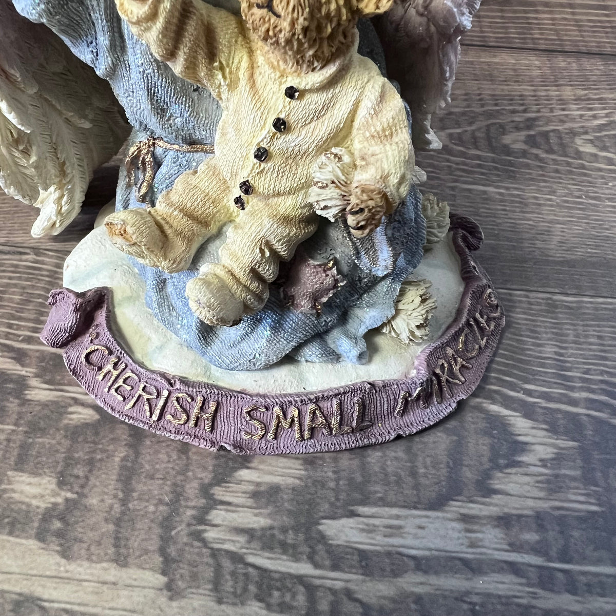 Decorative figurine of a teddy bear with a child, on a wooden surface.