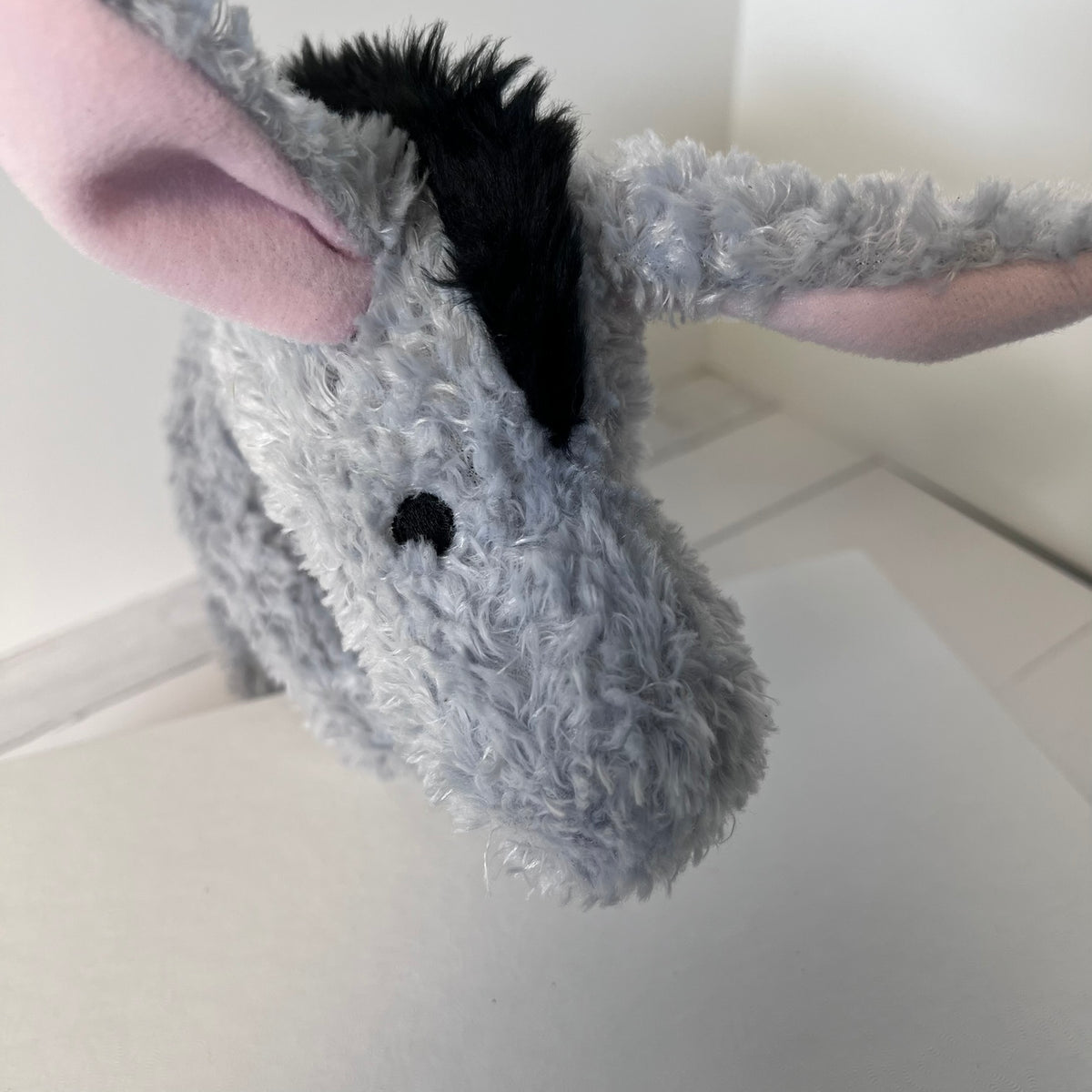 Plush donkey toy held by a person on a light-colored floor.
