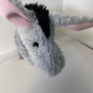 Plush donkey toy held by a person on a light-colored floor.