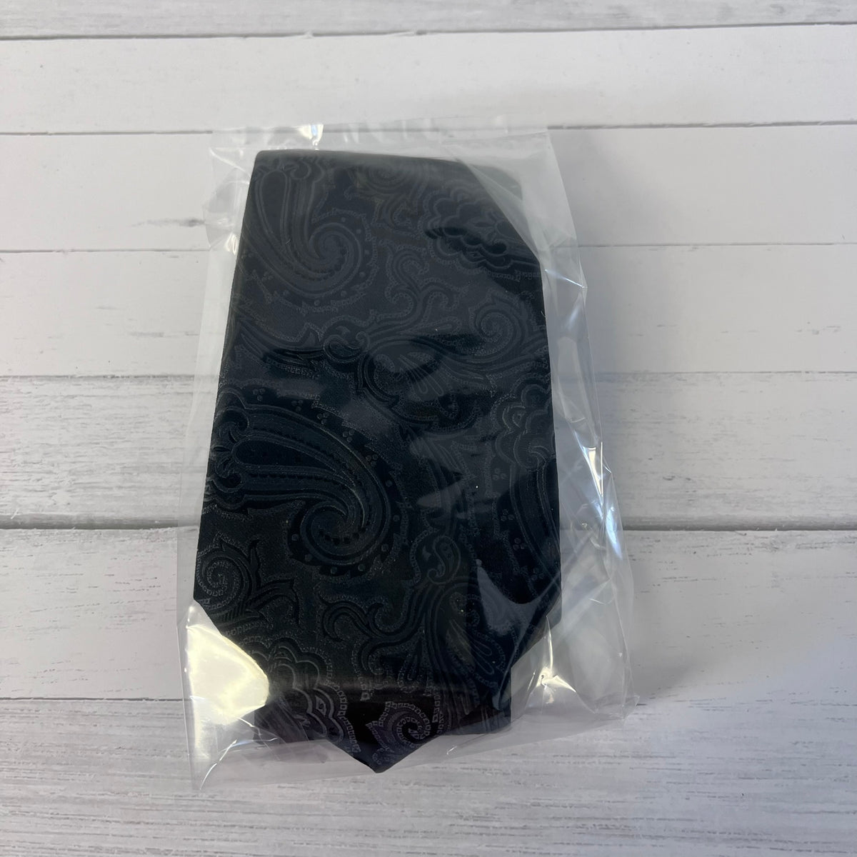 Black textured object in clear plastic packaging on a light wooden surface