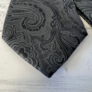 Black paisley patterned tie on a textured white surface