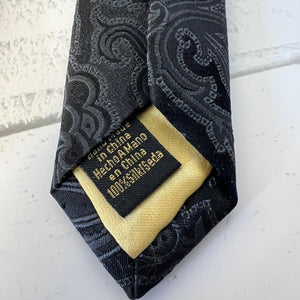 Black patterned tie with a gold label on a white background