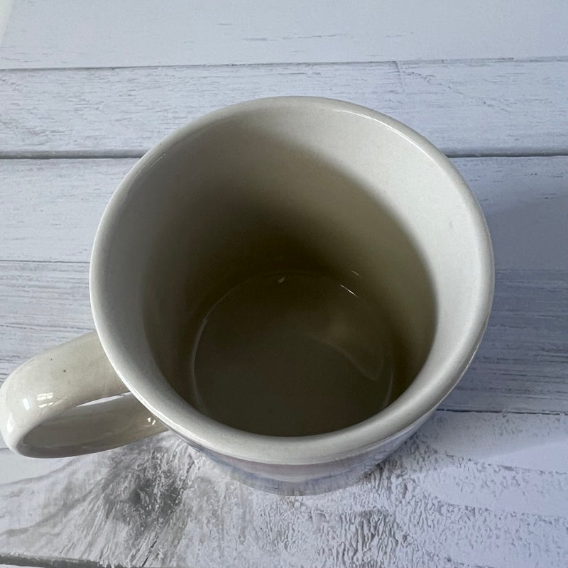 Empty white ceramic mug on a light wooden surface