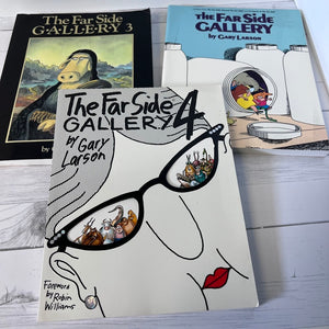 Three books from 'The Far Side Gallery' series by Gary Larson on a wooden surface.